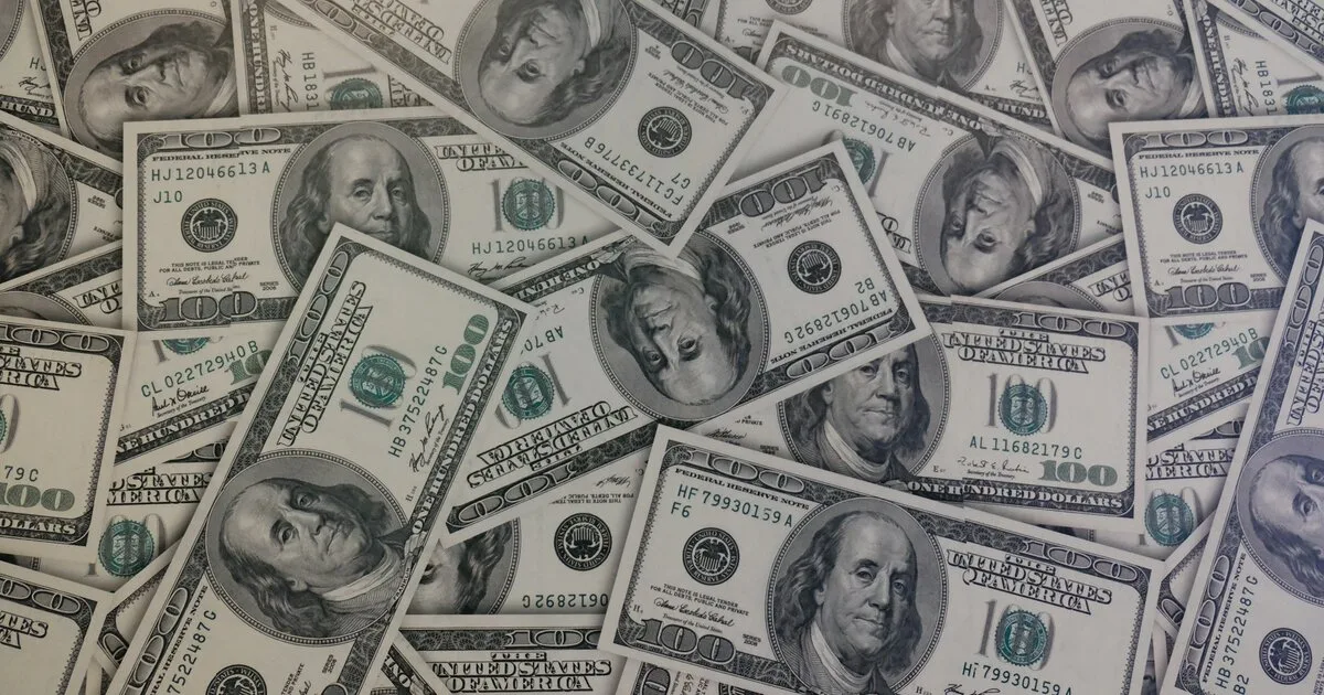 Scattered United States one hundred dollar bills covering a flat surface